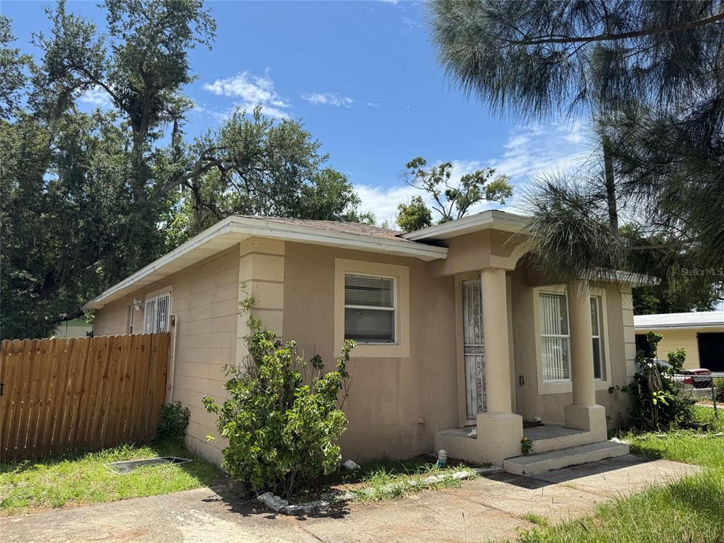 A single-story tan house with a flat roof, columns at the entrance, and a wooden fence — 2609 E EMMA STREET, TAMPA, FL