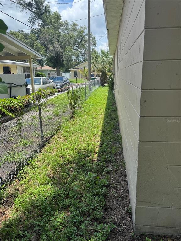A narrow strip of grass runs between a concrete block wall and a chain-link fence — 2609 E EMMA STREET, TAMPA, FL