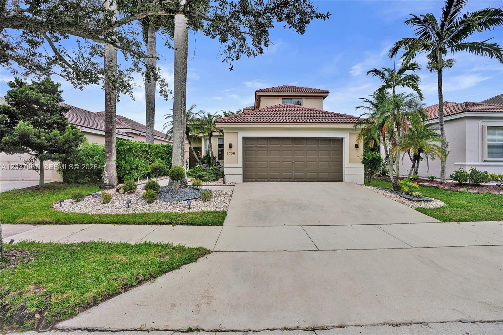 A single-story house with a brown garage door, tile roof, and palm trees in front — 1725 Winterberry Ln, Weston FL 33327, WESTON, FL