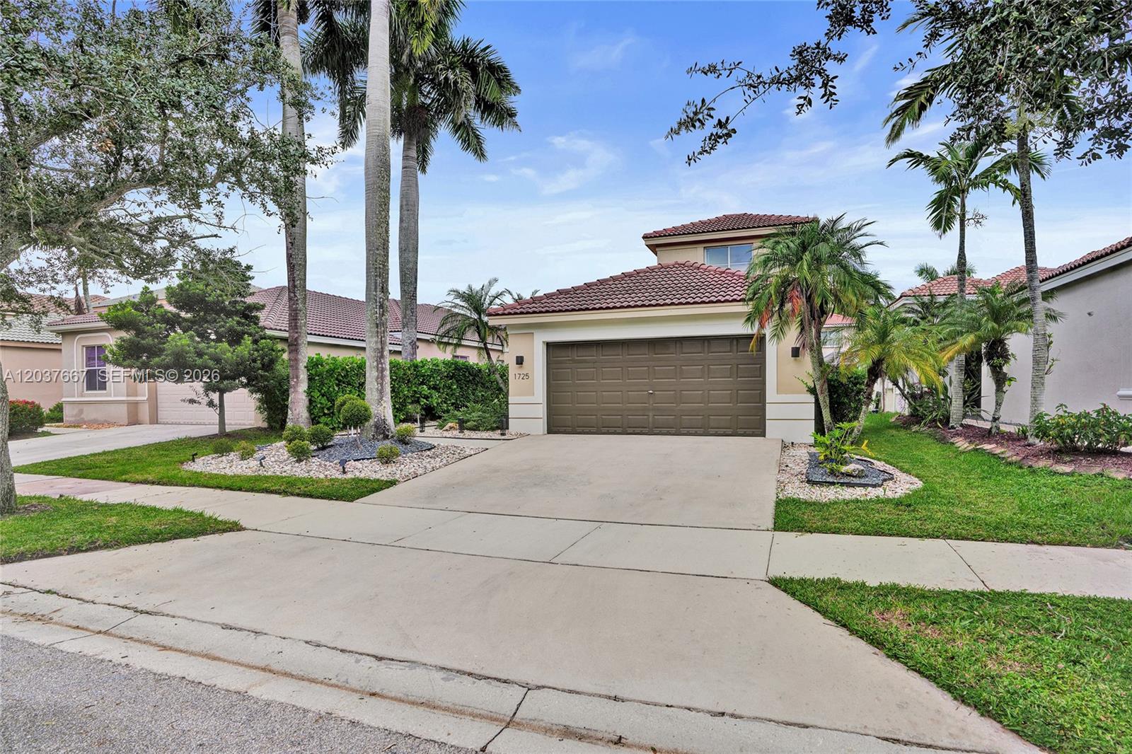 A single-story house with a brown garage door, tile roof, and palm trees in front — 1725 Winterberry Ln, Weston FL 33327, WESTON, FL