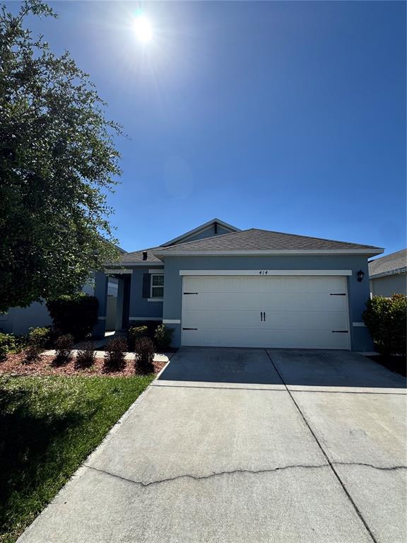 A blue single-story house features a two-car garage and a concrete driveway — 414 COOL SUMMER LANE, DAVENPORT, FL