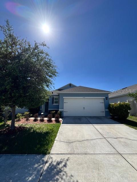 A single-story house with a two-car garage and a concrete driveway under a blue sky — 414 COOL SUMMER LANE, DAVENPORT, FL