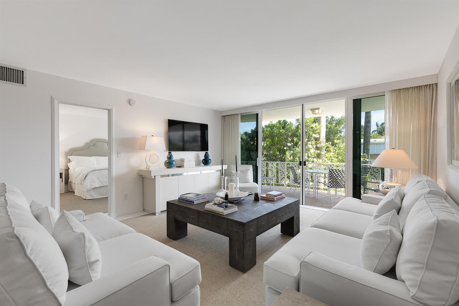 A living room with white sofas, a dark wood coffee table, and a balcony view — 227 Australian Avenue # 1e, Palm Beach FL 33480, PALM BEACH, FL