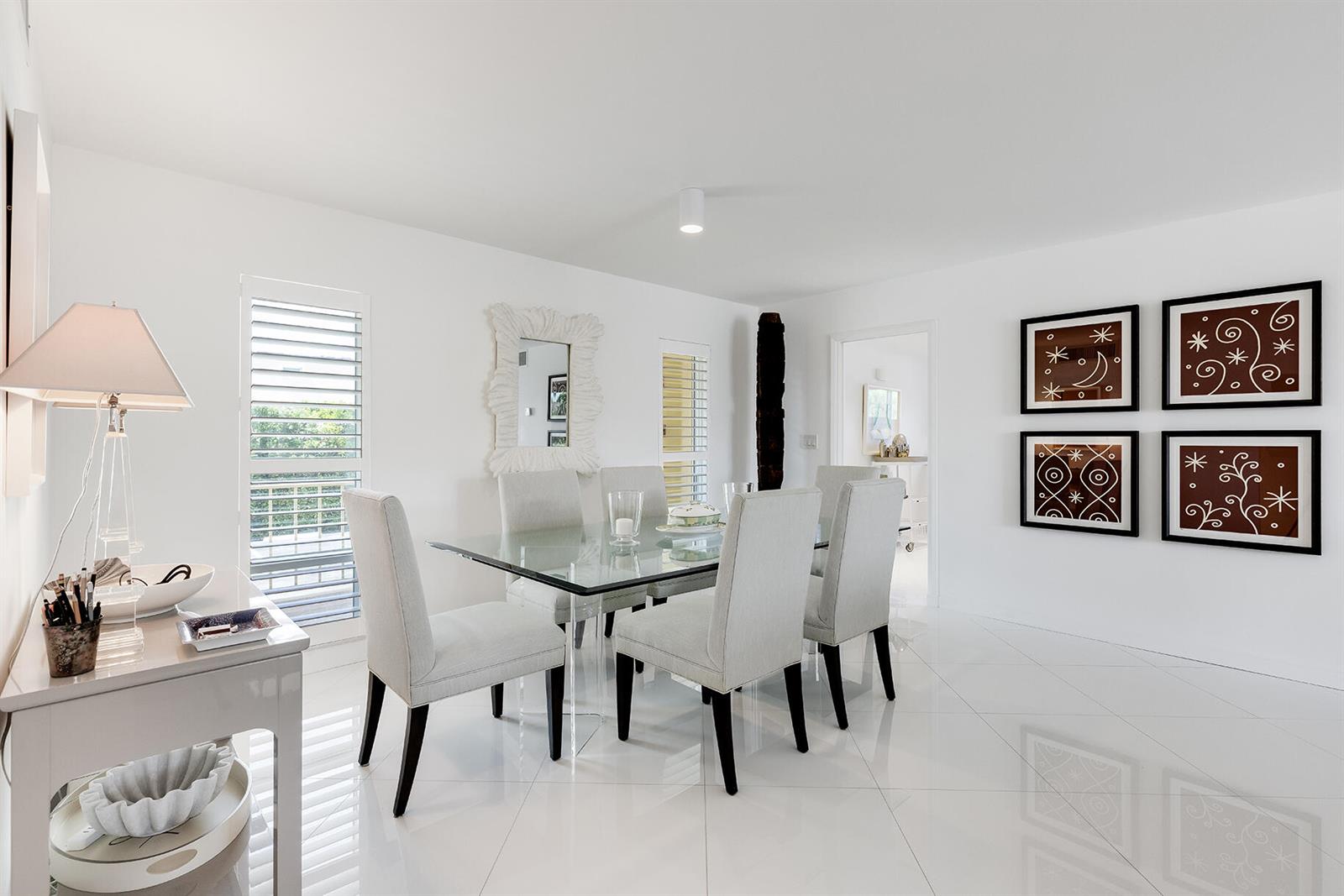 A dining room with a glass table, upholstered chairs, white tile floors, and wall art — 227 Australian Avenue # 1e, Palm Beach FL 33480, PALM BEACH, FL