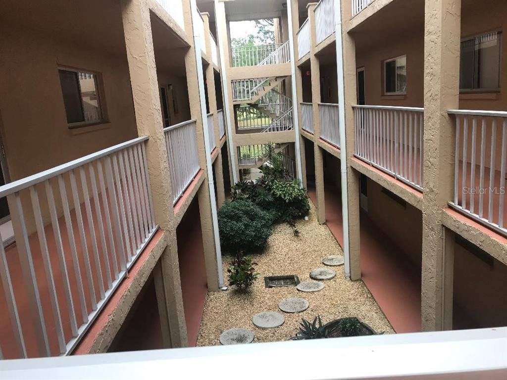 An elevated view of an apartment complex courtyard with a gravel garden and metal staircases — 1310 GLEN OAKS DRIVE E UNIT 385E, SARASOTA, FL