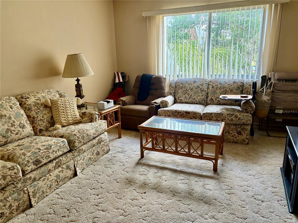 A living room features floral sofas, a brown recliner, a coffee table, and large windows — 1310 GLEN OAKS DRIVE E UNIT 385E, SARASOTA, FL