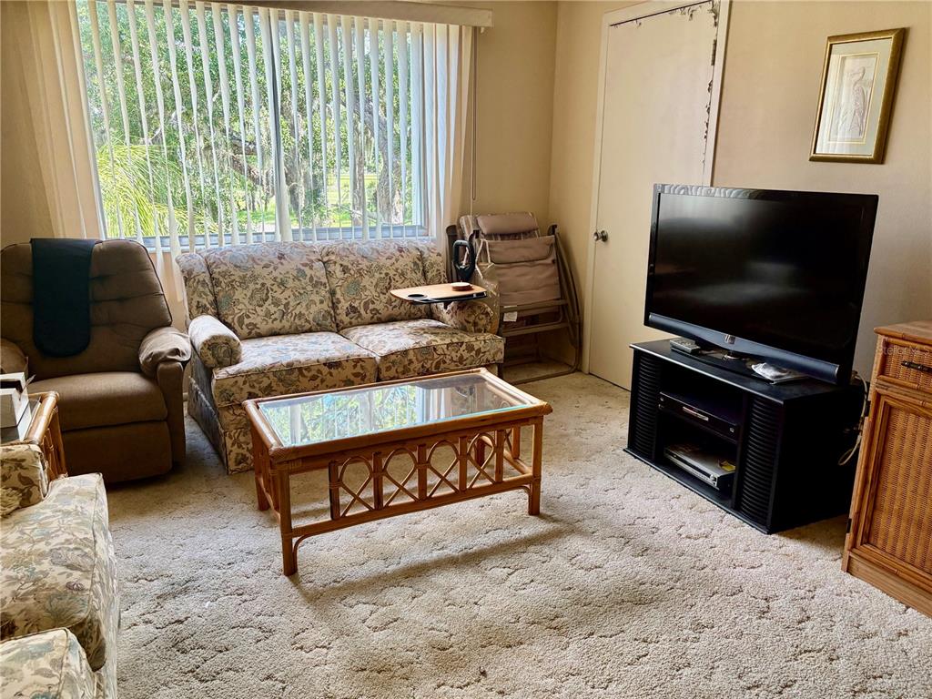 A living room features a floral sofa, a brown recliner, a coffee table, and a television — 1310 GLEN OAKS DRIVE E UNIT 385E, SARASOTA, FL