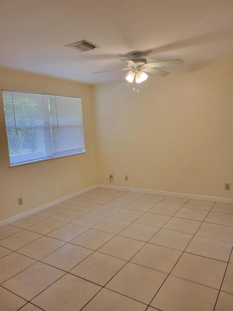 An empty room features light-colored walls, white tile flooring, a ceiling fan, and window blinds — 2227 Monroe Street # 2, Hollywood FL 33020, HOLLYWOOD, FL