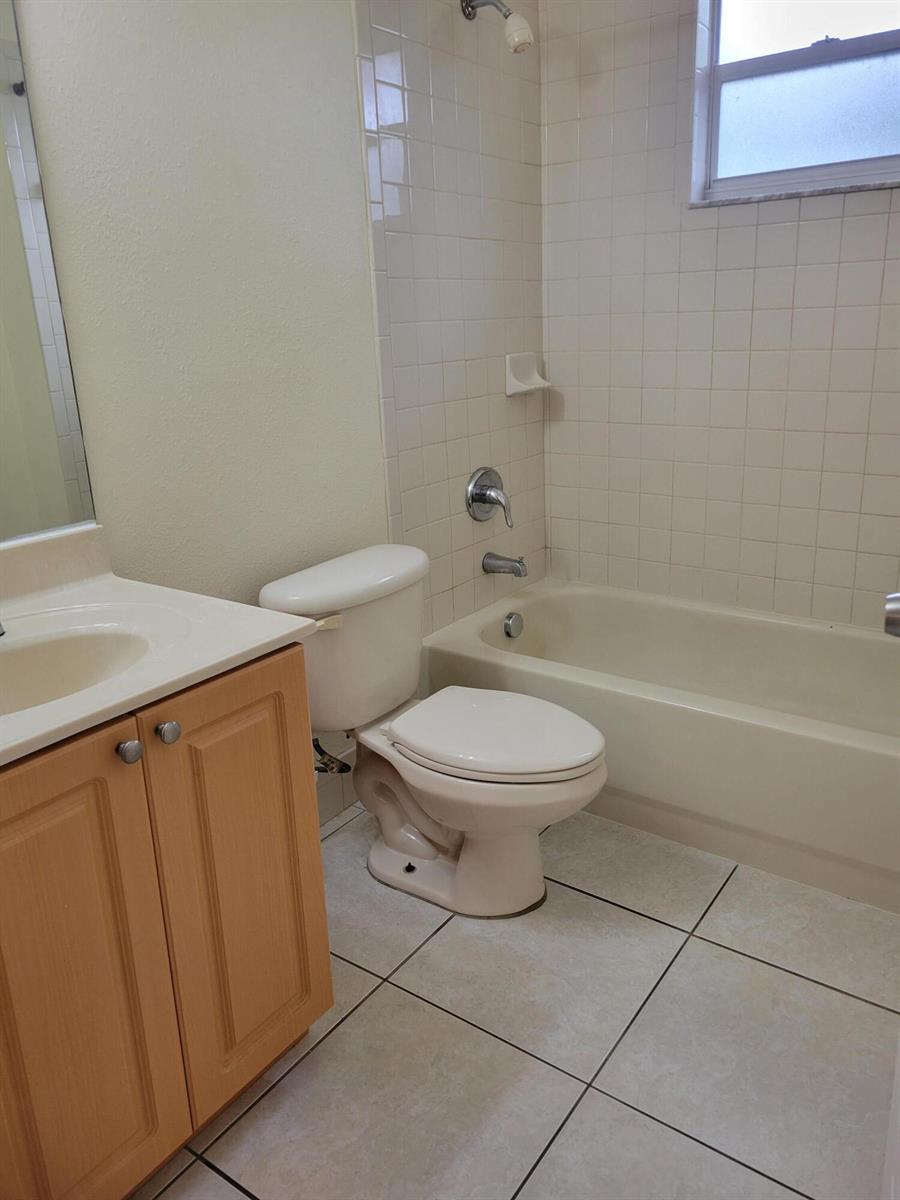 A bathroom features a vanity, a toilet, and a shower-tub combination with white tile walls — 2227 Monroe Street # 2, Hollywood FL 33020, HOLLYWOOD, FL