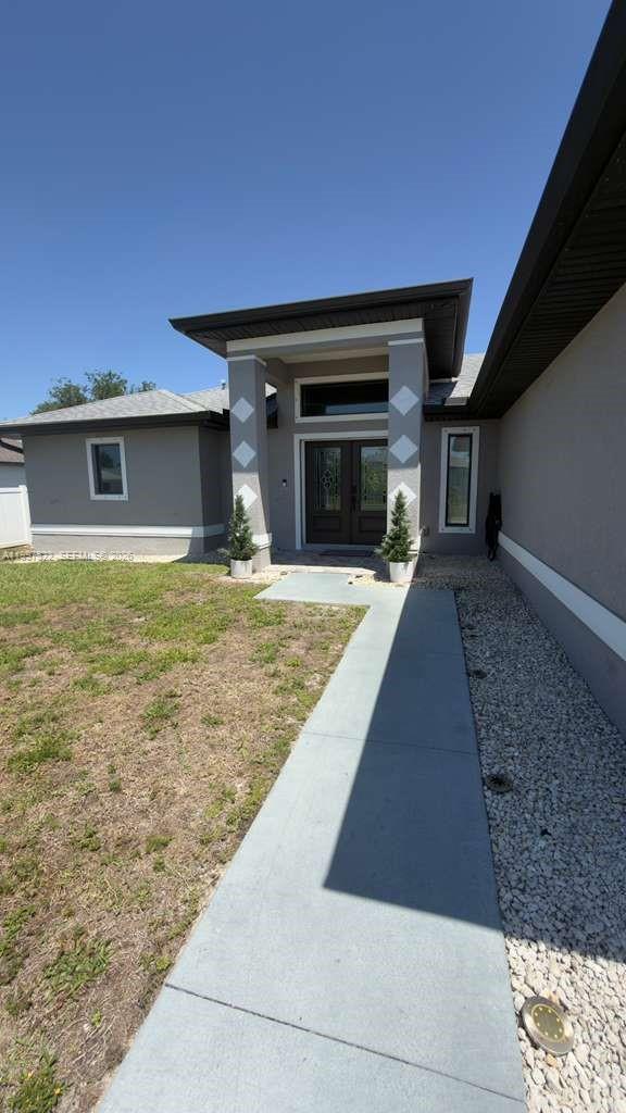 The exterior of a gray house features a covered entryway with two potted plants — 4407 SW 16th PL, Cape Coral FL 33914, CAPE CORAL, FL