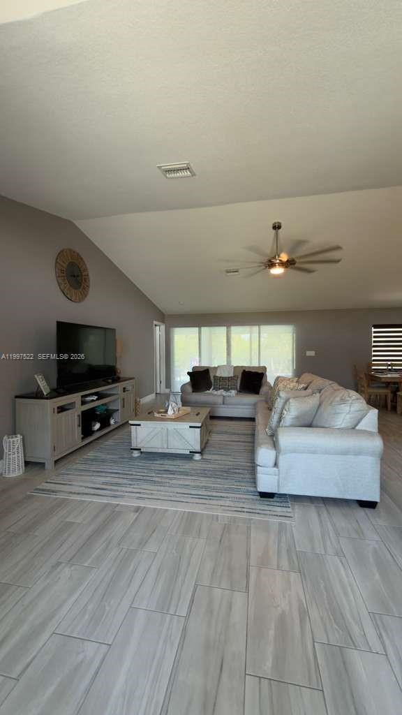 A living room features light-colored tile flooring, a gray sectional sofa, and a television console — 4407 SW 16th PL, Cape Coral FL 33914, CAPE CORAL, FL