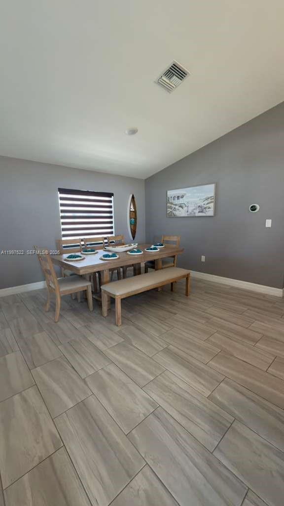 A dining room features a wooden table with chairs and a bench on tiled floors — 4407 SW 16th PL, Cape Coral FL 33914, CAPE CORAL, FL