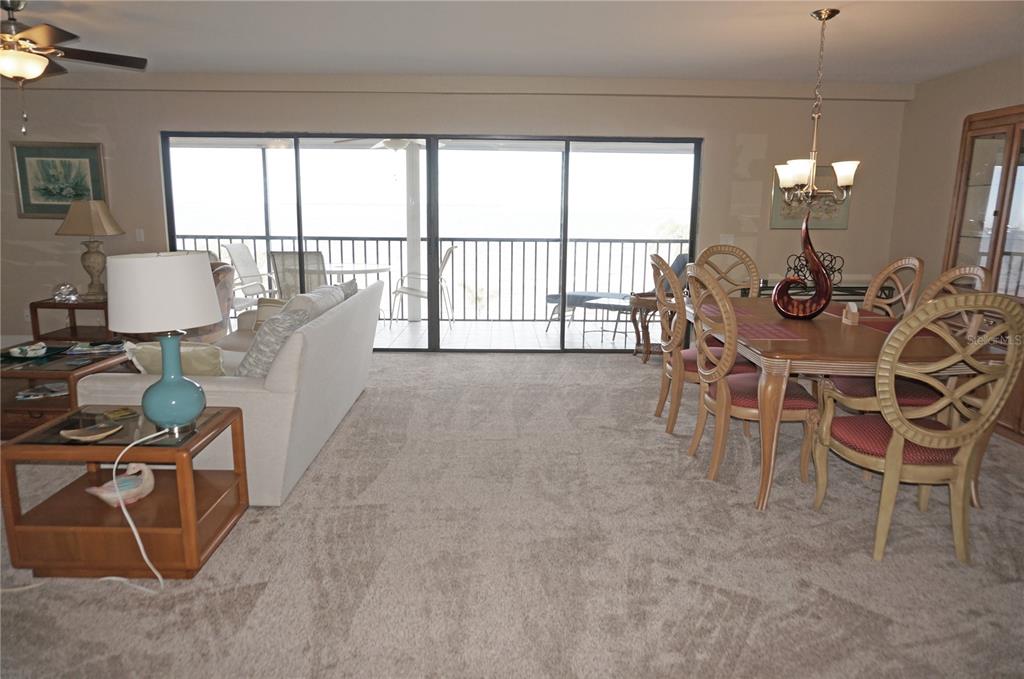A living and dining area features carpeted floors, a balcony view, and a wooden dining set — 1601 PARK BEACH CIRCLE UNIT 125/11, PUNTA GORDA, FL