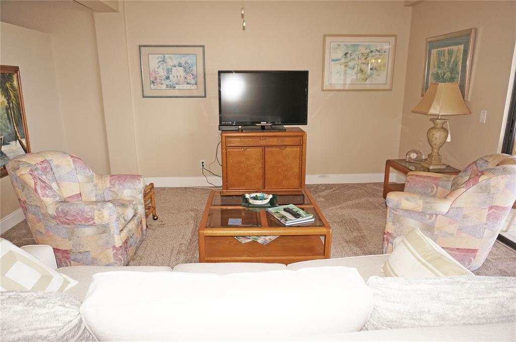 A living room features two patterned armchairs, a coffee table, and a television on a cabinet — 1601 PARK BEACH CIRCLE UNIT 125/11, PUNTA GORDA, FL