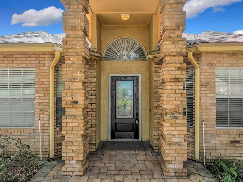 The front entrance of a brick house features a dark door with a decorative glass insert — 9144 GALLEON COURT, ORLANDO, FL
