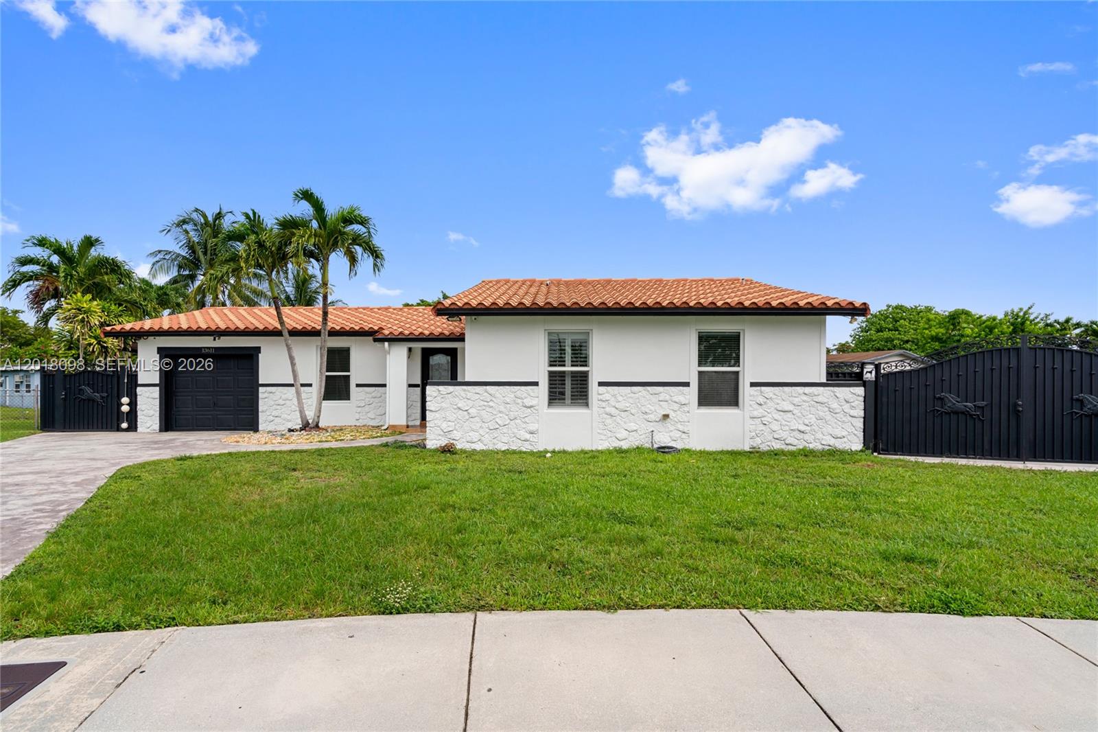 A single-story house with a white stucco facade, stone base, and a red tile roof — 13611 SW 77th St, Miami FL 33183, MIAMI, FL