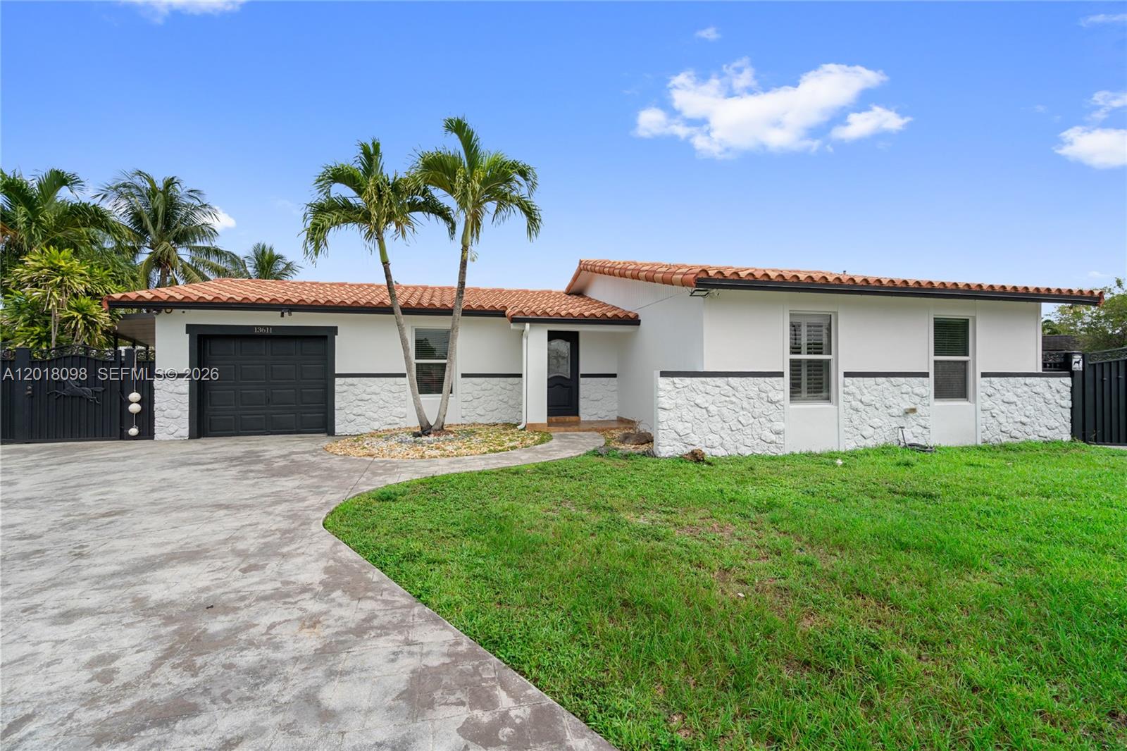 A single-story house features a white stucco exterior, stone accents, a tiled roof, and palm trees — 13611 SW 77th St, Miami FL 33183, MIAMI, FL