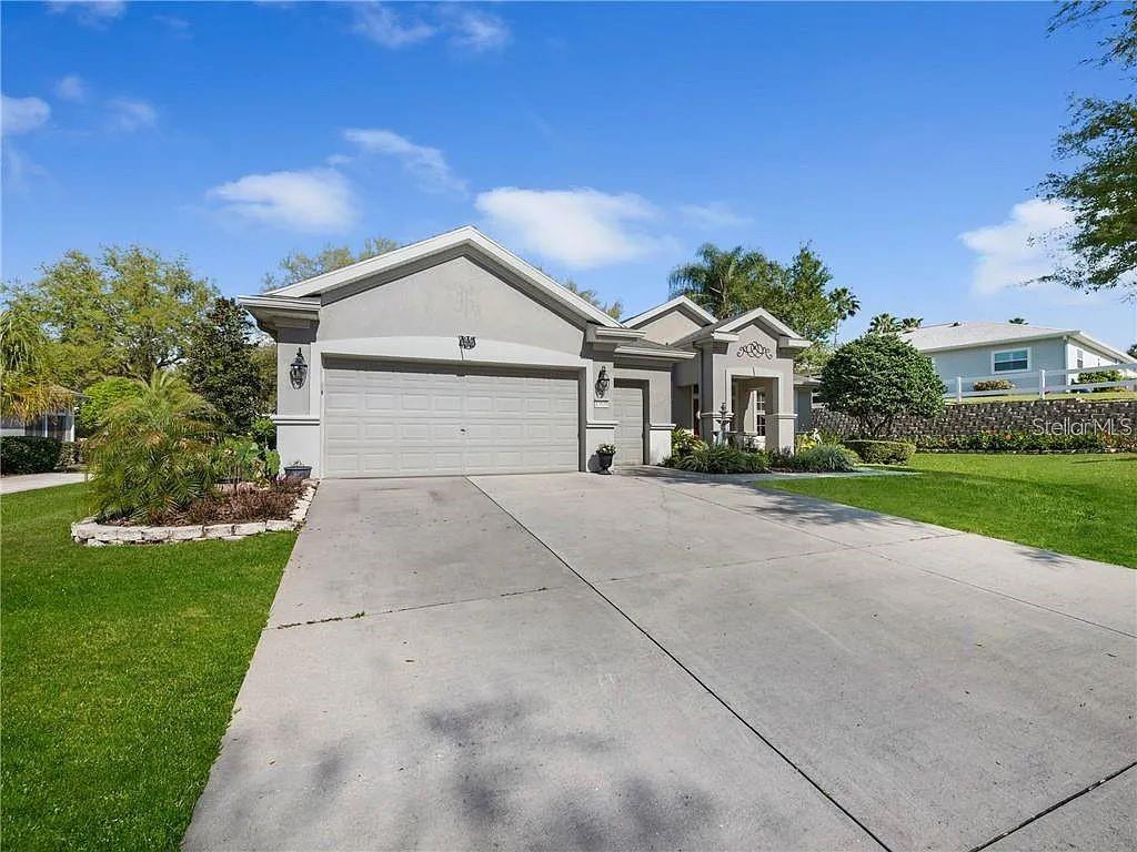 A single-story house with a gray exterior, a two-car garage, and a concrete driveway — 13650 SE 91ST AVENUE, SUMMERFIELD, FL