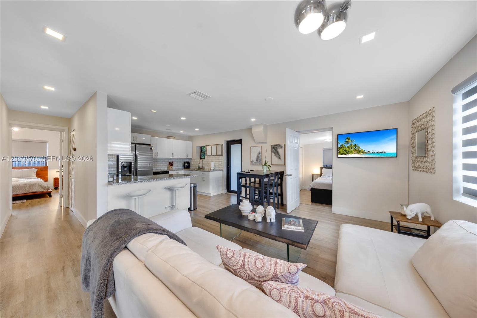 An open-concept living area features a white kitchen, dining table, and a sectional sofa — 5612 NW 11th Ave, Miami FL 33127, MIAMI, FL