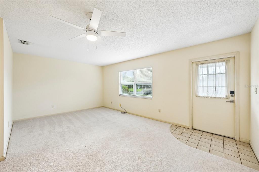 A room with beige carpet, a ceiling fan, a window, and a tiled entryway — 1902 DANDRIDGE STREET UNIT 29, SUN CITY CENTER, FL