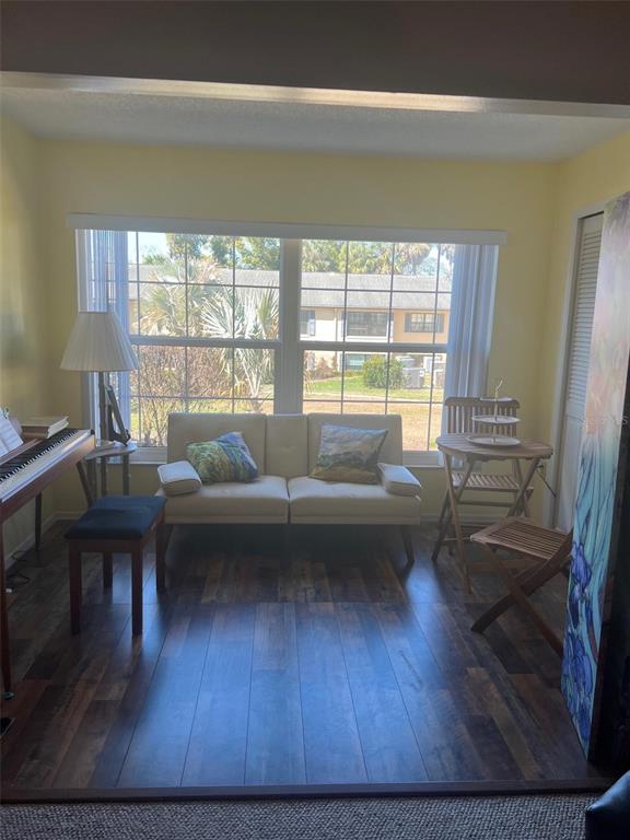 A sunroom features a small sofa, a piano, a wooden bistro set, and wood-look flooring — 110 N TREMAIN STREET UNIT 110, MOUNT DORA, FL