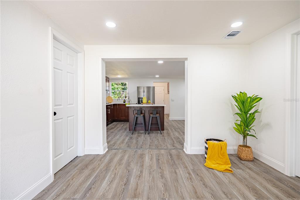 A view from a room with wood-look flooring looking through an opening into a kitchen — 11303 CHICAGO AVENUE, NEW PORT RICHEY, FL