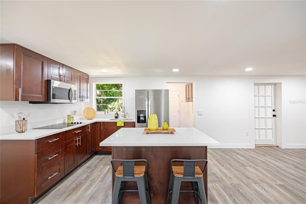 A kitchen with dark wood cabinets, white countertops, a central island, and wood-look flooring — 11303 CHICAGO AVENUE, NEW PORT RICHEY, FL