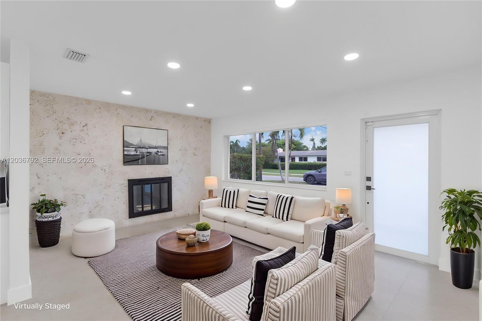 A living room features a stone fireplace wall, white sofa, striped chairs, and large windows — 8660 SW 125th Ter, Miami FL 33156, MIAMI, FL
