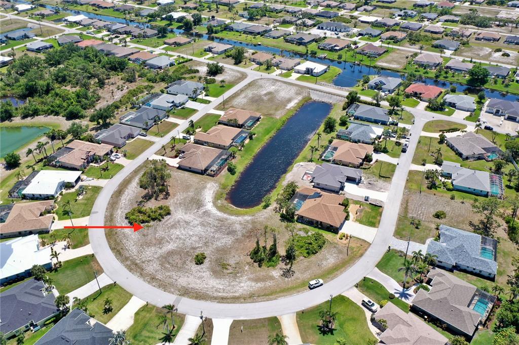 An aerial view shows a vacant residential lot situated within a curved suburban street — 13 MEDALIST WAY, ROTONDA WEST, FL
