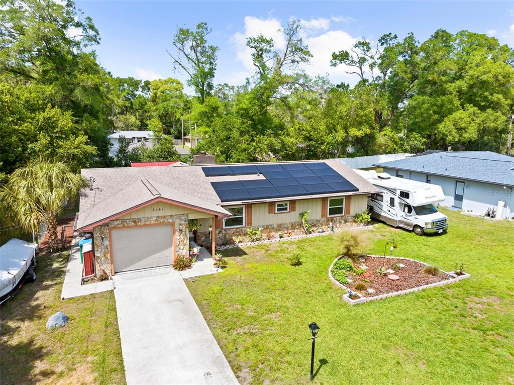 An aerial view of a single-story house with solar panels, a garage, and an RV parked — 6141 E DELL LANE, INVERNESS, FL