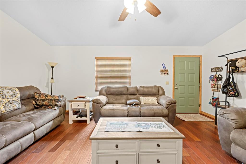 A living room features brown leather sofas, a coffee table, and hardwood flooring — 6141 E DELL LANE, INVERNESS, FL