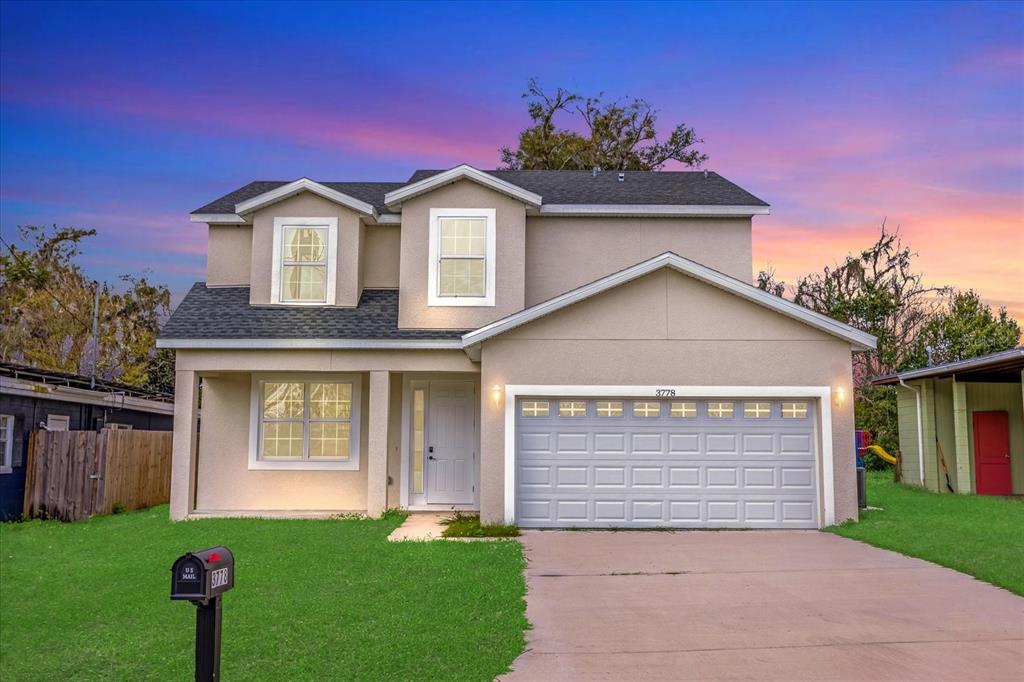A two-story suburban house with a beige stucco exterior, a garage, and a front lawn — 3778 MARTIN STREET, ORLANDO, FL
