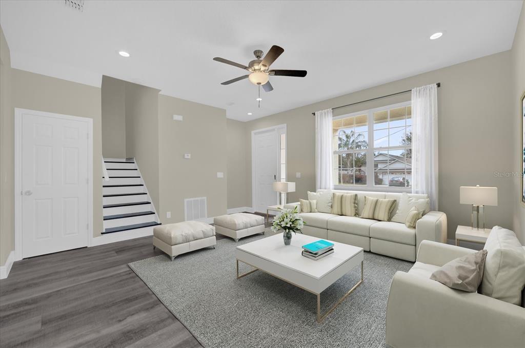 A living room with light walls, gray wood-look flooring, a white sofa, and a staircase — 3778 MARTIN STREET, ORLANDO, FL
