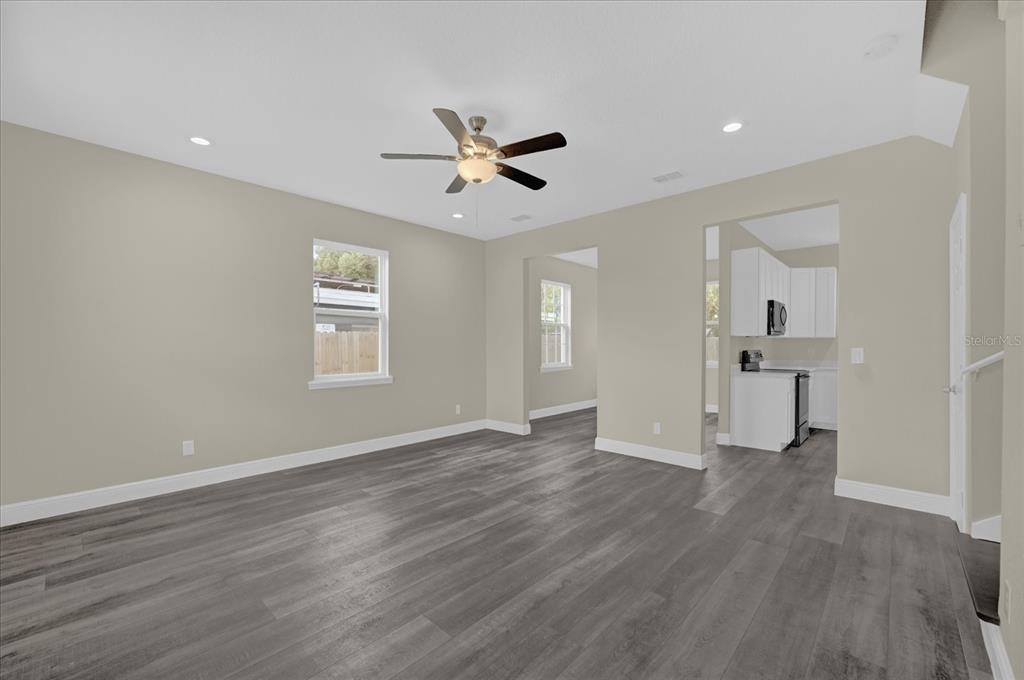 A living room with gray wood-look flooring, a ceiling fan, and an adjacent kitchen area — 3778 MARTIN STREET, ORLANDO, FL