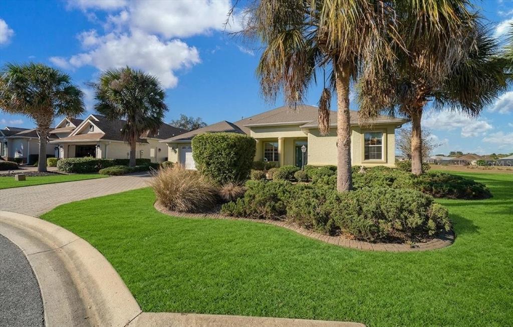 A single-story house with a paved driveway, green lawn, and palm trees under a blue sky — 8459 SW 84TH LOOP, OCALA, FL