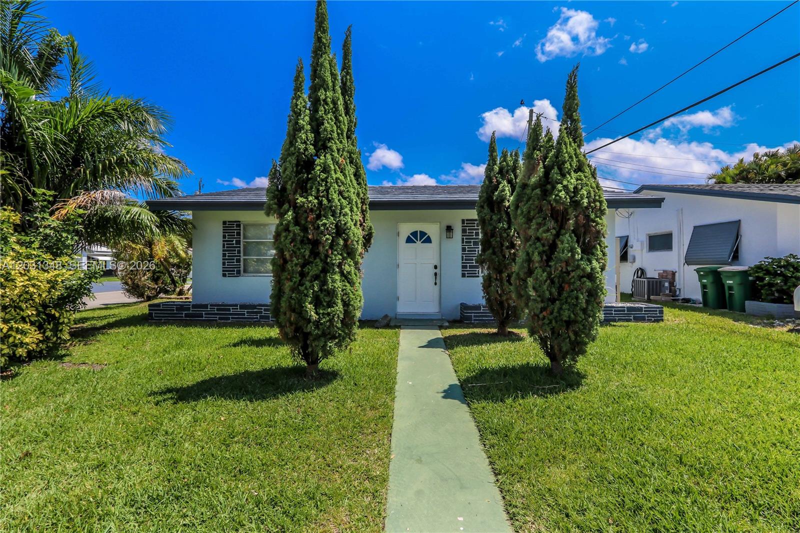 A single-story house with a white door, green walkway, and tall evergreen trees — 2700 NW 52nd Ct, Tamarac FL 33309, TAMARAC, FL