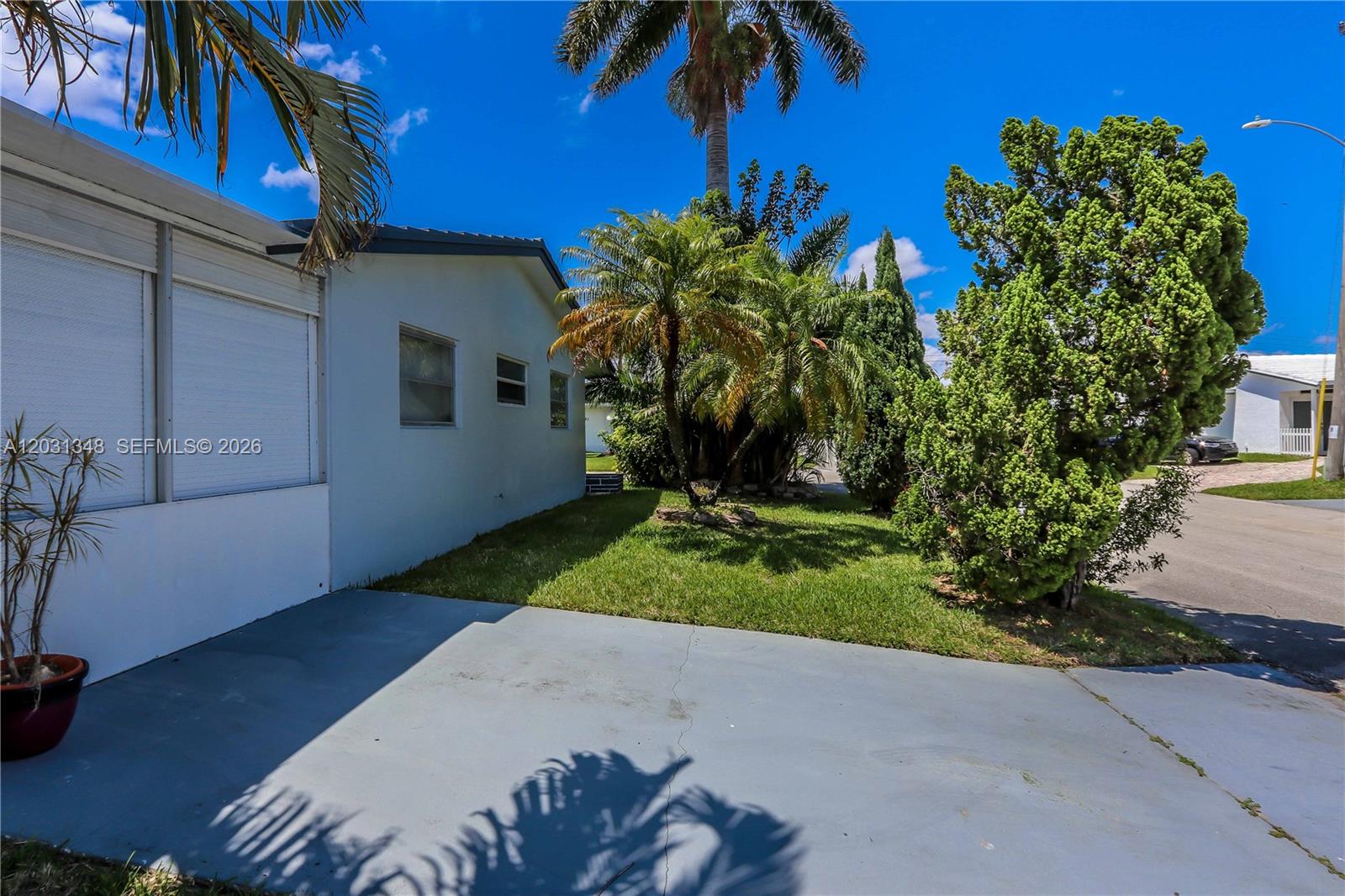 A light-colored house exterior features a concrete driveway, a small lawn, and palm trees — 2700 NW 52nd Ct, Tamarac FL 33309, TAMARAC, FL