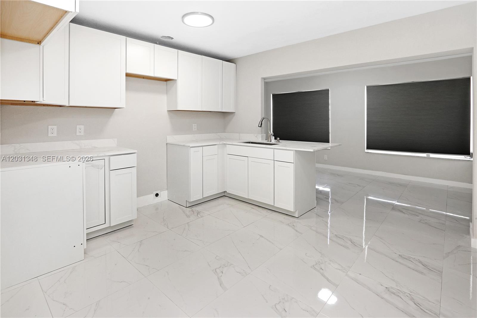 A kitchen features white cabinets, marble-look countertops, and light-colored tile flooring — 2700 NW 52nd Ct, Tamarac FL 33309, TAMARAC, FL