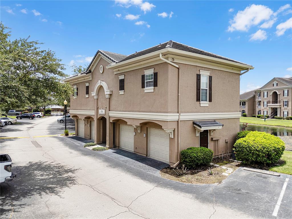 A two-story tan stucco building features multiple garage bays and a side entrance — 14340 FREDRICKSBURG DRIVE UNIT 701, ORLANDO, FL