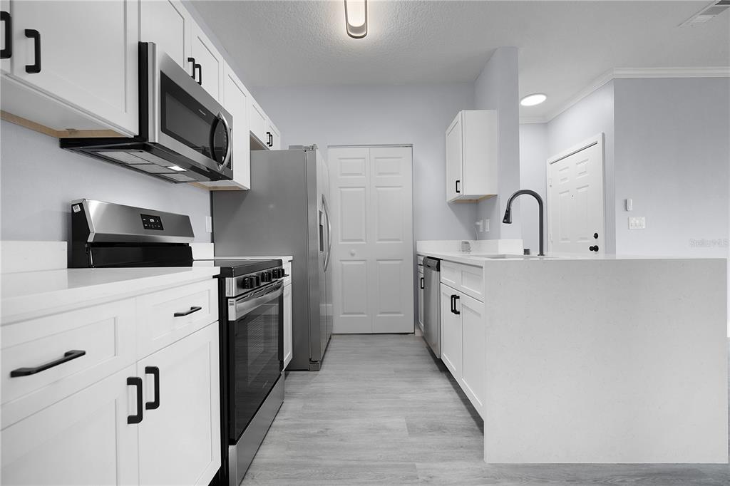 A modern kitchen features white cabinets, stainless steel appliances, and a white quartz island — 14340 FREDRICKSBURG DRIVE UNIT 701, ORLANDO, FL