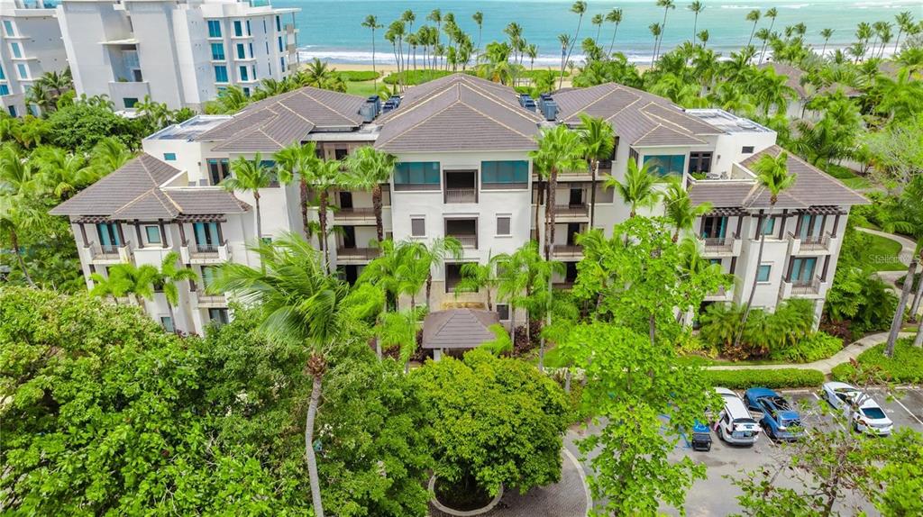 An aerial view of a multi-story resort building surrounded by palm trees near the ocean — Bahia Beach Golf Club LAS VENTANAS II UNIT 208, RIO GRANDE, PR