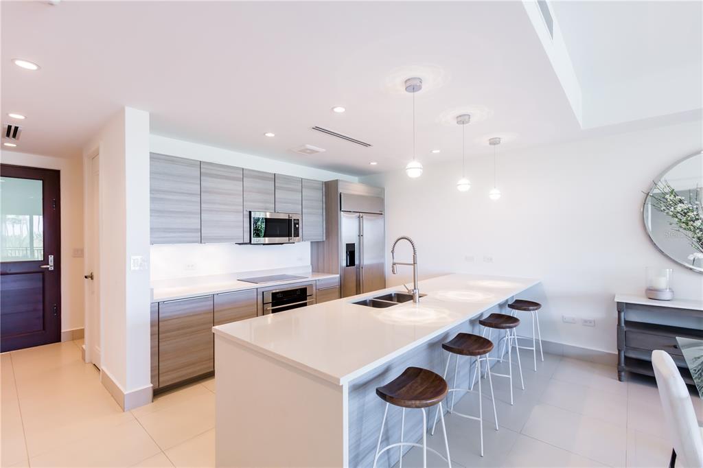 A modern kitchen features light wood cabinetry, a large white island, and four bar stools — Bahia Beach Golf Club LAS VENTANAS II UNIT 208, RIO GRANDE, PR
