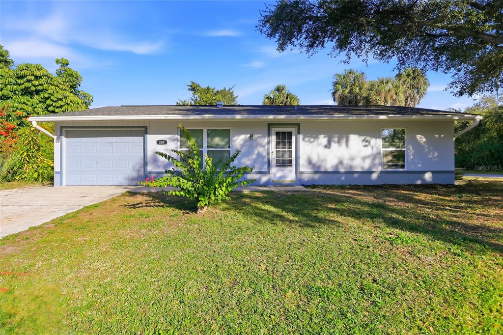 A single-story house with a light-colored exterior, a one-car garage, and a front lawn — 301 LAMBERT STREET, PORT CHARLOTTE, FL