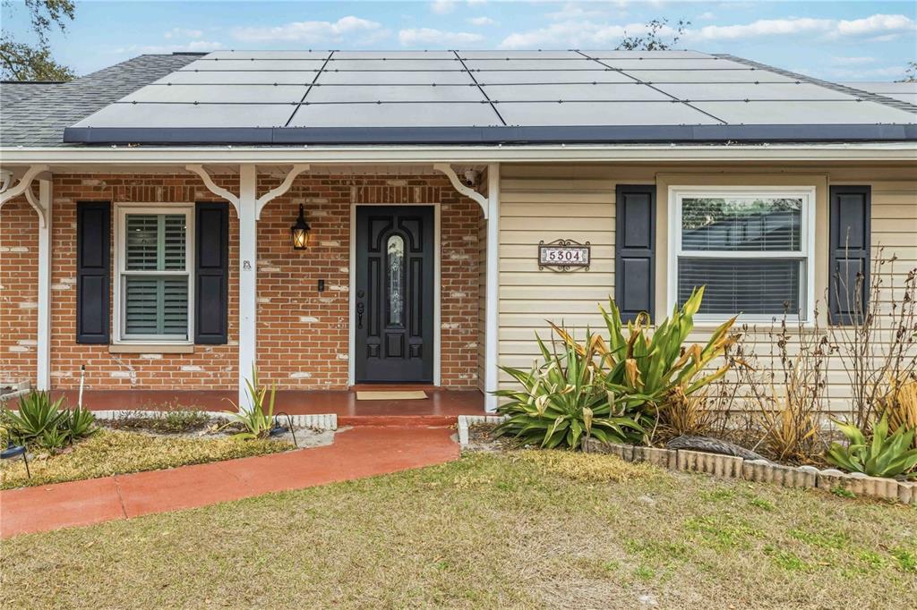 A single-story brick and siding house with a solar panel roof and a large lawn — 5304 ROSECREST CIRCLE, TAMPA, FL