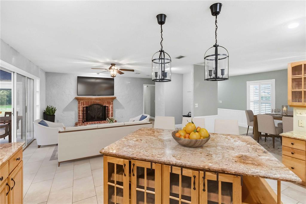 A kitchen island with a granite countertop overlooks a living room with a brick fireplace — 5304 ROSECREST CIRCLE, TAMPA, FL