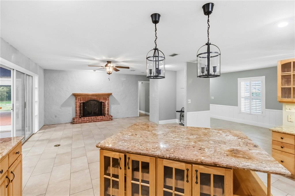 A kitchen island with granite countertops sits in front of a living area with a fireplace — 5304 ROSECREST CIRCLE, TAMPA, FL