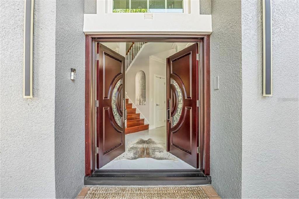 A view through an open double front door into a foyer with a wooden staircase — 6527 BAYBORO COURT, ORLANDO, FL