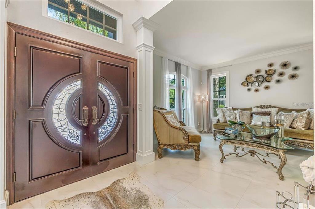 A foyer with double wood doors leads into a living room with tile floors — 6527 BAYBORO COURT, ORLANDO, FL