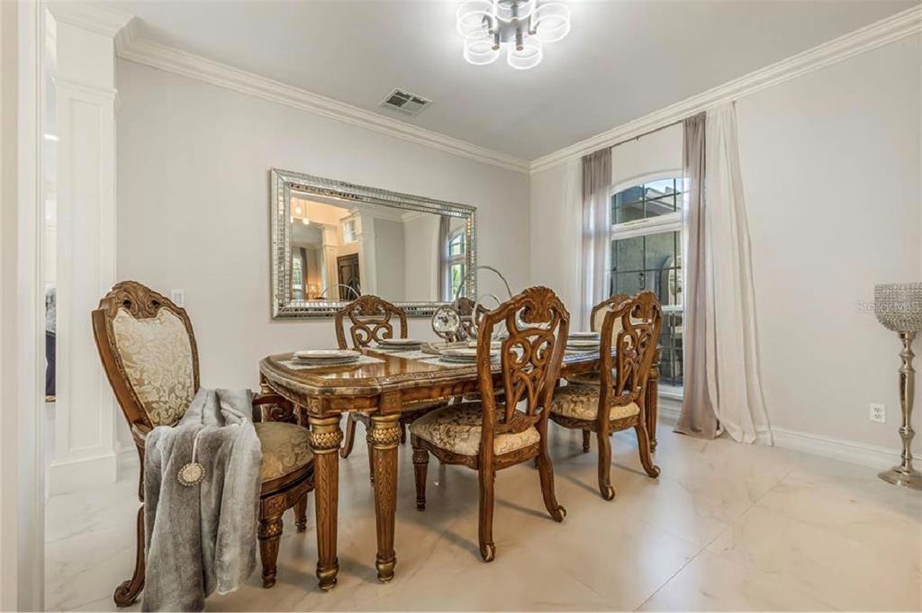 A formal dining room features a wooden table, ornate chairs, a large mirror, and chandelier — 6527 BAYBORO COURT, ORLANDO, FL