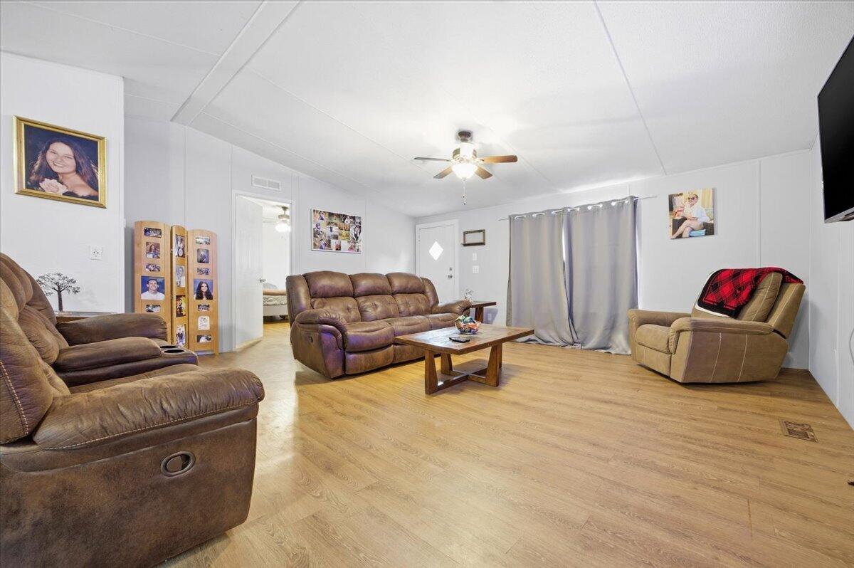 A living room features light wood-look flooring, a brown sofa, a recliner, and a ceiling fan — 194 Keuka Road, FL 32148, FL